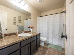 Bathroom featuring visible vents, toilet, vanity, and a textured ceiling