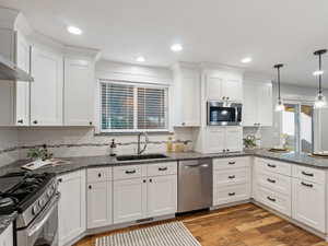 Kitchen featuring light hardwood / wood-style flooring, stainless steel appliances, sink, and white cabinets