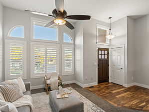 Living room with a towering ceiling, dark wood-type flooring, and ceiling fan