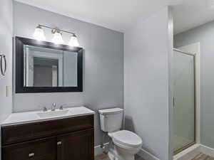 Bathroom with vanity, a shower with shower door, and toilet