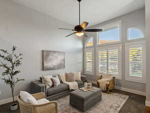 Living room featuring dark colored carpet, high vaulted ceiling, plenty of natural light, and ceiling fan