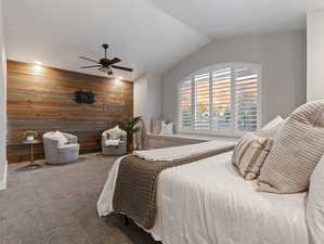 Bedroom with wood walls, carpet, vaulted ceiling, and ceiling fan