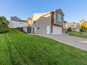 View of home's exterior with a storage shed, a yard, and a garage