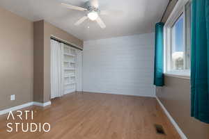 Unfurnished bedroom with ceiling fan, a textured ceiling, and light wood-type flooring