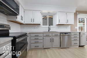 Kitchen with white cabinetry, sink, stainless steel appliances, and light hardwood / wood-style floors