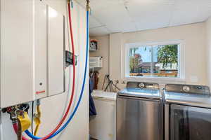 Clothes washing area featuring tankless water heater and separate washer and dryer