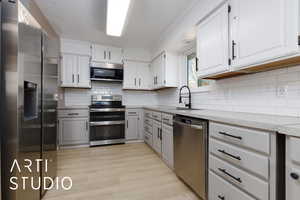 Kitchen featuring stainless steel appliances, sink, white cabinets, and light wood-type flooring