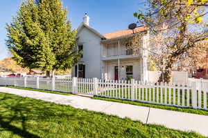 View of front facade with a balcony and a front yard