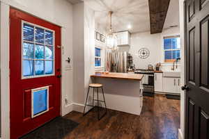 Kitchen with sink, white cabinetry, decorative light fixtures, dark hardwood / wood-style flooring, and stainless steel appliances