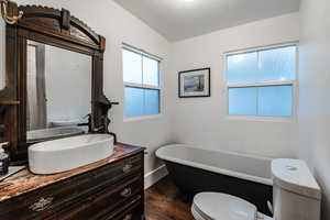 Bathroom featuring a bathing tub, toilet, oversized vanity, and hardwood / wood-style floors