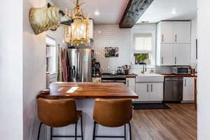 Kitchen featuring dark hardwood / wood-style floors, wood counters, sink, appliances with stainless steel finishes, and tasteful backsplash