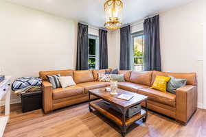 Living room with light hardwood / wood-style floors and a notable chandelier