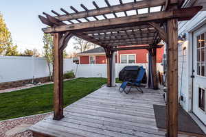 Wooden terrace featuring a pergola and a yard