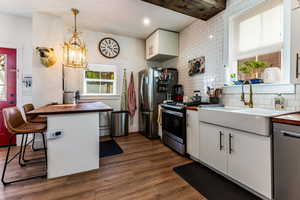 Kitchen with appliances with stainless steel finishes, white cabinets, plenty of natural light, and dark hardwood / wood-style flooring