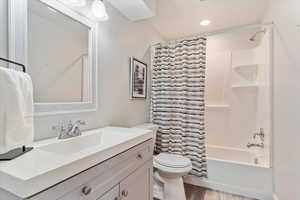 Full bathroom with vanity, toilet, wood-type flooring, and shower / bath combination with curtain