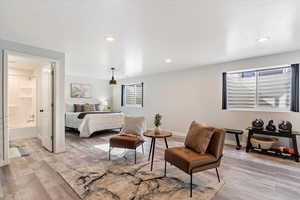 Bedroom featuring multiple windows, ensuite bath, and light wood-type flooring