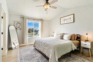 Bedroom with vaulted ceiling, light wood-type flooring, and ceiling fan