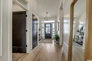 Foyer entrance with light hardwood / wood-style floors and an inviting chandelier