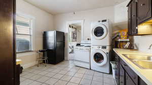 Washroom with stacked washer / dryer, sink, and light tile patterned floors