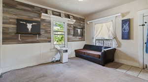 Sitting room featuring light carpet, wood walls, and a textured ceiling