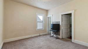 Interior space with a textured ceiling and light colored carpet