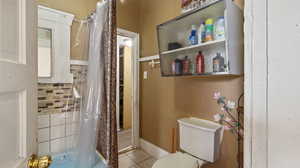 Bathroom featuring tile patterned floors, a shower with shower curtain, and toilet