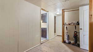 Hallway featuring light carpet and wooden walls