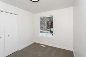 Unfurnished bedroom with a closet and dark colored carpet