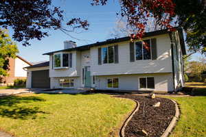 Raised ranch featuring a front yard and a garage