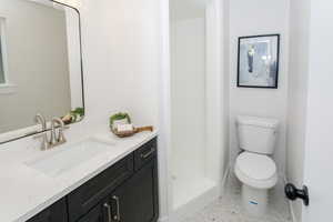 Bathroom featuring vanity, toilet, tile patterned floors, and walk in shower