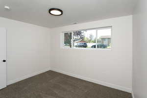 Spare room featuring a textured ceiling and dark colored carpet