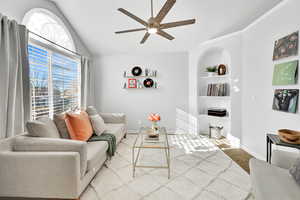 Living room featuring carpet flooring, ceiling fan, built in features, and vaulted ceiling