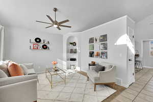 Living room with built in shelves, ceiling fan, and light tile patterned flooring