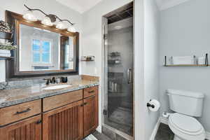 Bathroom with tile patterned floors, an enclosed shower, vanity, crown molding, and toilet