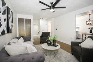 Living room with a textured ceiling, light hardwood / wood-style flooring, and ceiling fan with notable chandelier