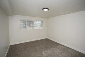 Carpeted empty room featuring a textured ceiling