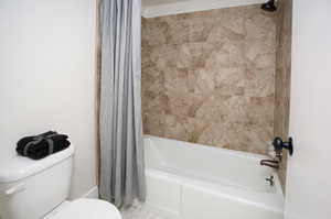 Bathroom featuring toilet and shower / tub combo with curtain