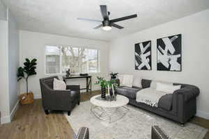 Living room featuring a textured ceiling, hardwood / wood-style flooring, and ceiling fan