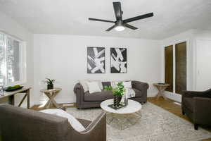 Living room featuring ceiling fan, wood-type flooring, and a textured ceiling