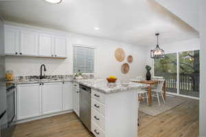 Kitchen featuring white cabinets, light hardwood / wood-style floors, light stone counters, and stainless steel appliances