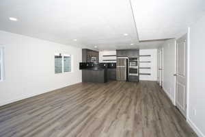 Unfurnished living room with dark wood-type flooring and a textured ceiling