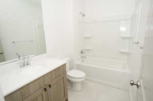 Full bathroom with vanity, tile patterned floors, toilet, and shower / bathtub combination