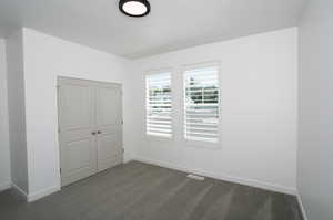 Unfurnished bedroom featuring a closet and dark carpet