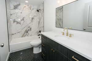 Full bathroom with vanity, tiled shower / bath, toilet, and tile patterned flooring