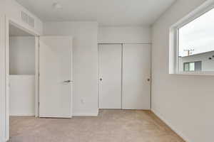 Unfurnished bedroom featuring light carpet and a closet