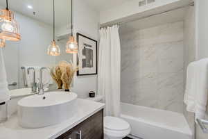 Full bathroom featuring vanity, shower / tub combo with curtain, and toilet