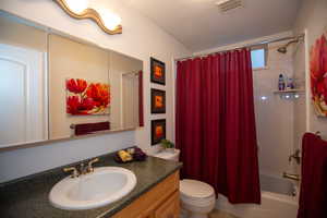 Full bathroom featuring vanity, toilet, a textured ceiling, and shower / bath combo