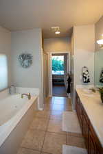 Master bathroom with vanity, a tub, a textured ceiling, and tile patterned flooring