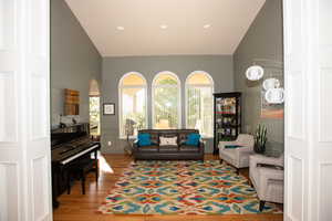 Sitting room with hardwood / wood-style floors and high vaulted ceiling