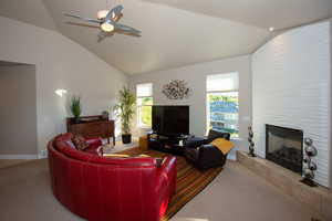 Carpeted living room with lofted ceiling, a tile fireplace, and ceiling fan